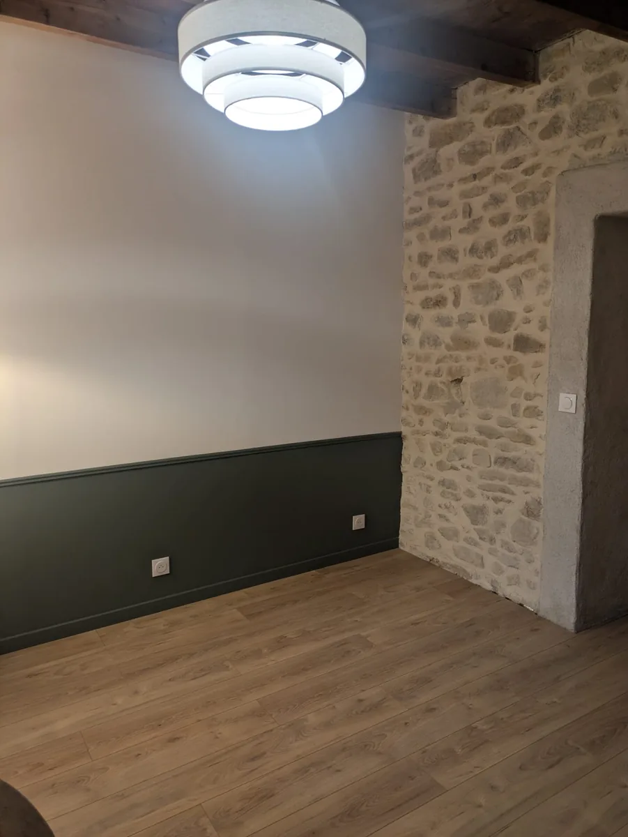 La pièce livrée après rénovation énergétique : murs finis, plafond isolé et pierre laissée apparente