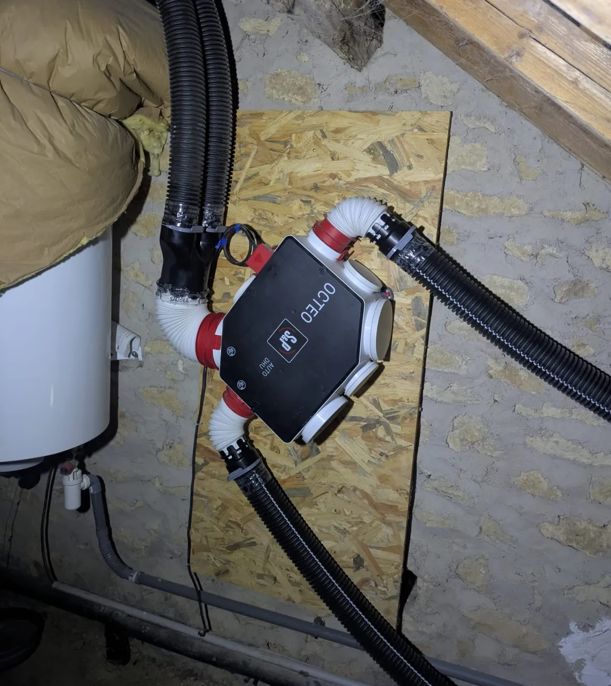 Caisson de VMC hygroréglable installé sur un mur en pierre, gaines raccordées