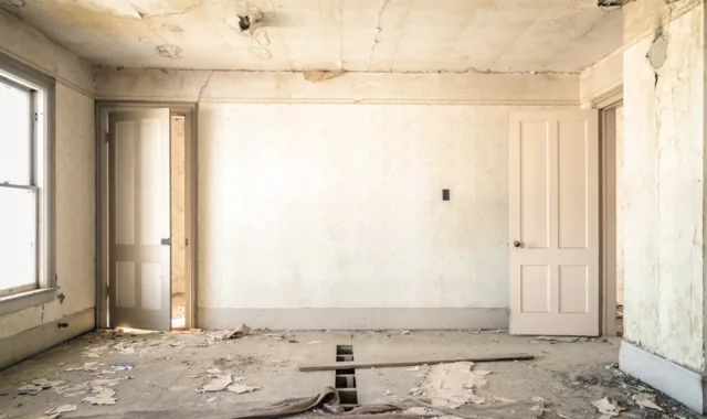 Pièce d'un logement ancien avant travaux, enduit écaillé et plancher ouvert
